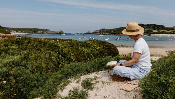 Woman sketching the view up to Cromwell Castle, Tresco, Isles of Scilly